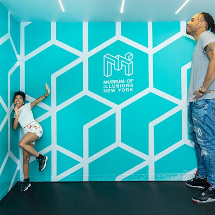 Two people in a geometric room at the Museum of Illusions New York, creating an optical illusion of size difference.