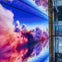 A digital display showing colorful clouds reflected on a glossy floor in a modern indoor setting.