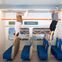 Two people appear to hang upside down, gripping a bar in a room designed like a train, labeled Museum of Illusions.