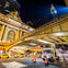Night scene of Grand Central Terminal with yellow taxis and a white truck, under an overpass with the Chrysler Building in view.