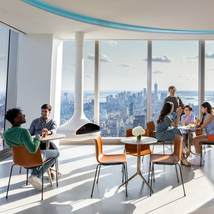 People seated at tables in a modern lounge with floor-to-ceiling windows offering a cityscape view.