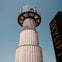 A tall cylindrical observation tower with a glass platform at the top, people are visible, and a sign reads "SKYLIFT."