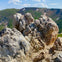 Jagged rock formations in the foreground with green hills and a blue sky in the background.