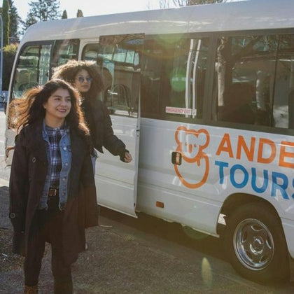 Two women exiting a white van with "Andes Tours" written on the side, parked on a sunny street.