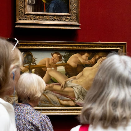 A group of people observing a classical painting in a museum. The artwork depicts mythological figures.