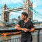 A tourist is having his photo taken outside the Tower Bridge.