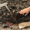 A child's hand reaches towards an exposed ancient wooden artifact partially buried in dirt, with some cloth and a bag nearby.