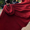 A person wearing a flowing red cloak outdoors, with other people visible in the background.