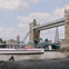 A view of Tower Bridge with a tour boat labeled 'Tower of London River Tour' on the Thames and the Shard in the background.
