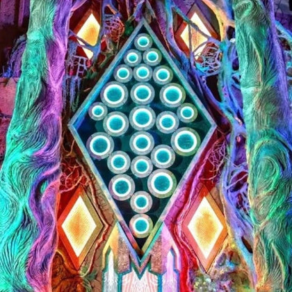A glowing, colorful geometric design featuring illuminated circles within a diamond shape, surrounded by organic shapes.