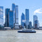 A ferry labeled "NY Waterway" travels on a river with modern skyscrapers in the background under a clear blue sky.