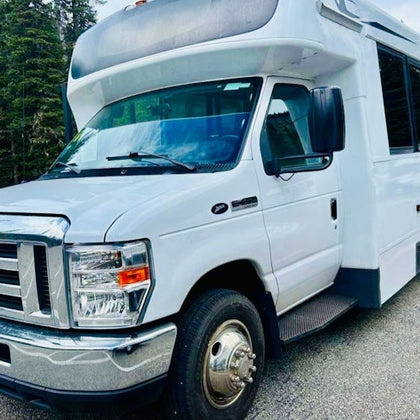 A white recreational vehicle is parked on a paved surface, with trees visible in the background.