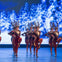 Performers dressed as reindeer dance on stage with a snowy forest backdrop.