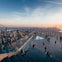 A rooftop observation deck with people enjoying the view of a cityscape during sunset.