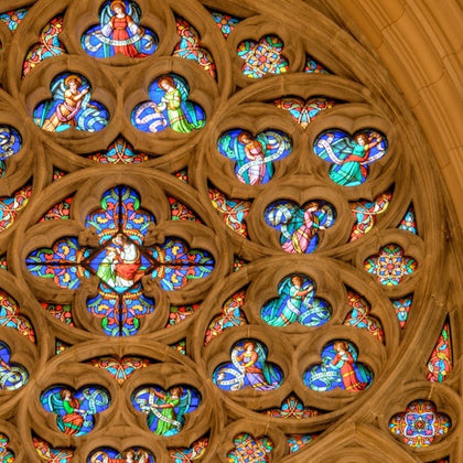 A close-up view of a cathedral's rose window with intricate stained glass and ornate stone tracery.