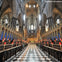Interior of a grand cathedral with tall vaulted ceilings, ornate wooden choir stalls, and a checkered floor leading to an elaborate altar.
