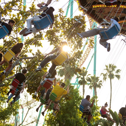 People enjoying a colorful teacup ride at an amusement park, with smiling riders and decorative surroundings.