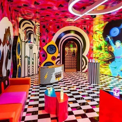 A vibrant room with colorful walls, checkered flooring, modern furniture, and abstract artwork, creating a lively atmosphere.