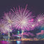 Bright fireworks illuminating a city waterfront at night with skyscrapers and reflections on the water.