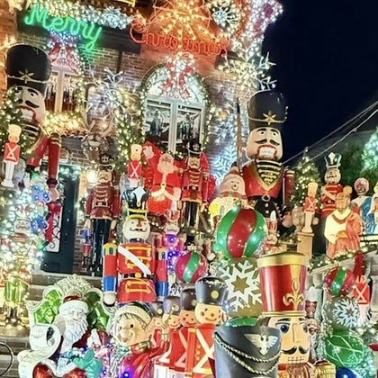A house decorated with numerous Christmas-themed ornaments, including nutcrackers, lights, and festive figures at night.