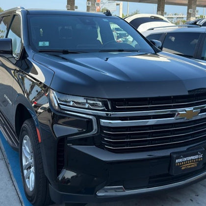 A black Chevrolet SUV parked in a lot, with "Rivas Enterprises LLC" on the front license plate holder.