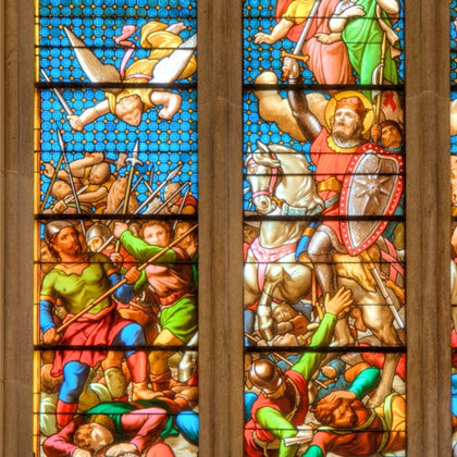 A stained glass window depicting a medieval battle scene with soldiers, a horse, and a knight holding a shield.