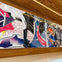 A large, colorful abstract mural with geometric patterns and shapes on a wooden wall inside a modern, well-lit space.