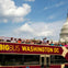 A double-decker tour bus labeled 'Big Bus Washington DC' with passengers, passing by the U.S. Capitol on a sunny day.