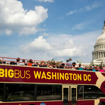 A double-decker tour bus labeled 'Big Bus Washington DC' with passengers, passing by the U.S. Capitol on a sunny day.