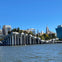 A waterfront structure with white, curved supports resembling tulips, set against a cityscape with tall buildings under a clear sky.
