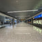Spacious, modern airport terminal with polished floors, rows of seats, flight information screens, and signs reading "CANADA."