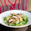 A plate of Caesar salad topped with grilled chicken strips and croutons, set against a colorful, patterned background.
