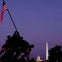 Silhouette of a statue of soldiers raising a flag, with the Washington Monument and Capitol building in the background.