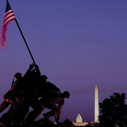 Silhouette of a statue of soldiers raising a flag, with the Washington Monument and Capitol building in the background.