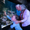 Two older adults and a young girl enjoy observing seahorses and coral in a large aquarium.