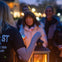 A tour guide holding a lantern while guests gather around to hear ghost stories