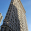 A tall, triangular-shaped historic building with ornate details, set against a clear blue sky.