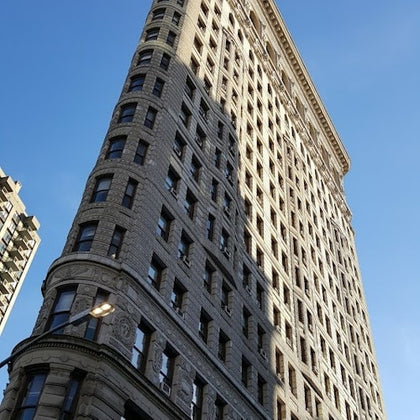 A tall, triangular-shaped historic building with ornate details, set against a clear blue sky.