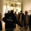 A group of people in a museum setting, with a guide wearing a 'VoxCity' jacket explaining exhibits to the group.