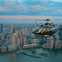 A black helicopter flying over a cityscape, with tall buildings and waterfront area visible below under a cloudy sky.