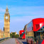Red double-decker buses on a bridge with the Big Ben clock tower in the background under a clear blue sky.