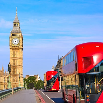 Red double-decker buses on a bridge with the Big Ben clock tower in the background under a clear blue sky.