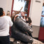 A person takes a photo of three people posing with a large sculpture of a gorilla's hand in an indoor space.