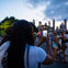 Person taking a photo of a city skyline with a crowd of people in the foreground during dusk.