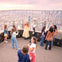 People enjoying the view from an observation deck at sunset, with a cityscape visible through the railing.